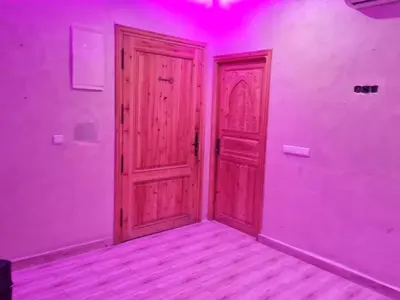 an empty room with a wooden door and purple lights at Hostel Ghali & Private Rooms Gueliz in Marrakech