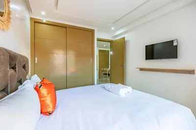a bedroom with a white bed with an orange pillow at New ! Appartement Bella ,Terrasse,Fibre Obtique in Marrakech