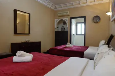 a bedroom with two beds with red sheets and a mirror at HOTEL CTM in Marrakech