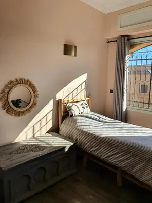 two beds in a bedroom with a mirror and a window at Maison Mamdy Rooftop in Marrakech