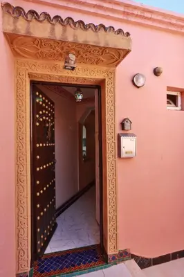 an entrance to a pink building with a wooden doorway at Résidence Assiyahia avec piscine Marrakech in Marrakech