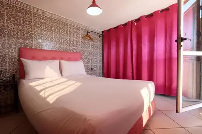 a bedroom with a large bed with a pink curtain at Résidence Assiyahia avec piscine Marrakech in Marrakech