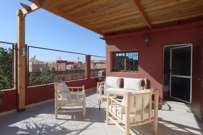 a patio with two chairs and a couch on a balcony at Résidence Assiyahia avec piscine Marrakech in Marrakech