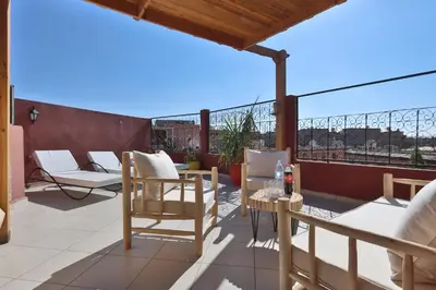 a patio with chairs and tables on a roof at Résidence Assiyahia avec piscine Marrakech in Marrakech