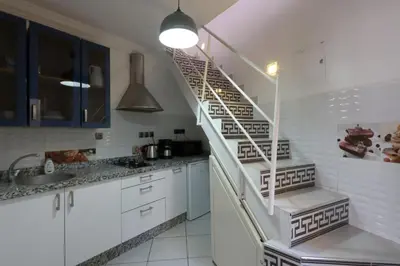 a kitchen with white cabinets and a spiral staircase at Résidence Assiyahia avec piscine Marrakech in Marrakech