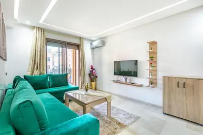 a living room with a green couch and a tv at Élégant Appartement , Terrasse in Marrakech