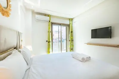 a bedroom with a white bed with a tv on the wall at Élégant Appartement , Terrasse in Marrakech