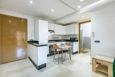 a kitchen with white cabinets and a table at Élégant Appartement , Terrasse in Marrakech
