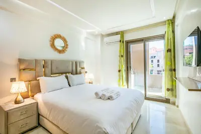 a bedroom with a large white bed and a window at Élégant Appartement , Terrasse in Marrakech