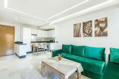 a living room with a green couch and a table at Élégant Appartement , Terrasse in Marrakech