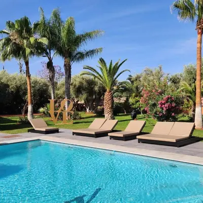 a swimming pool with lounge chairs and palm trees at Domaine K Marrakech in Marrakech