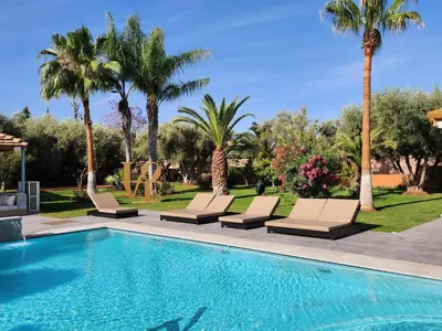 a swimming pool with lounge chairs and palm trees at Domaine K Marrakech in Marrakech