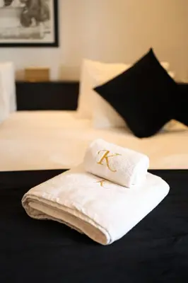 a white towel with a k on it sitting on a bed at Domaine K Marrakech in Marrakech