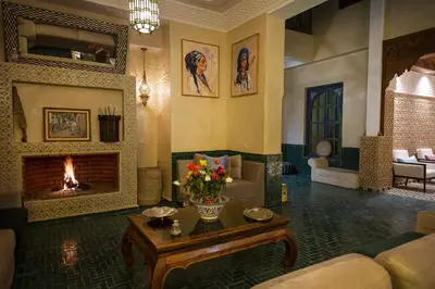 a living room with a fireplace and a couch and a table at Riad Atrium & Spa in Marrakech