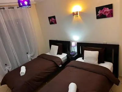 two beds sitting in a room with two at Magnifique Appartement spacieux confort propre familial 2 chambres salon et salle a manger a 20mn a pied de place jemaa el fina 4 piscines dans espace de Golf a 12 mn en voitures l entree est gratuit pour la clientele ouvert entre 10h et 20h in Marrakech
