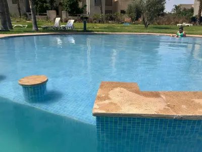 a large blue swimming pool with a person in the background at Havre de Paix Piscine Lagon & parc in Marrakech