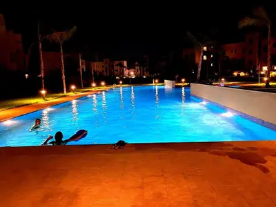 a person laying in a swimming pool at night at Havre de Paix Piscine Lagon & parc in Marrakech
