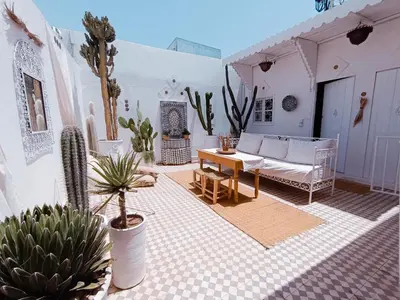 a patio with a couch and a table and cactus at STUDIO BLANCO MÉDINA AVEC TERRASSE in Marrakech