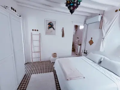 a white bedroom with a large bed and a ladder at STUDIO BLANCO MÉDINA AVEC TERRASSE in Marrakech