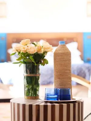 a vase of flowers and a bottle of water on a table at Riad Afous in Marrakech