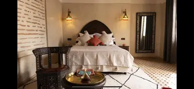 a bedroom with a bed with white sheets and red pillows at Riad Afous in Marrakech