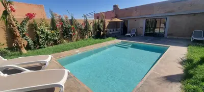 a swimming pool with two chairs next to a house at city garden Kech in Marrakech