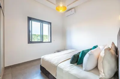 a white bedroom with a bed with a window at Villa Dalia, Personnels et option piscine in Marrakech