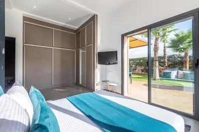 a bedroom with a large bed and a sliding glass door at Villa Dalia, Personnels et option piscine in Marrakech