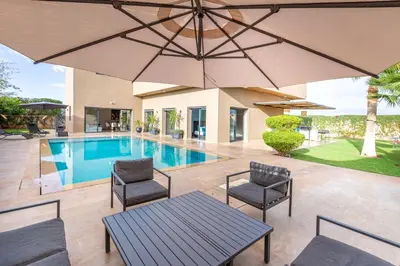 a patio with an umbrella and a swimming pool at Villa Dalia, Personnels et option piscine in Marrakech