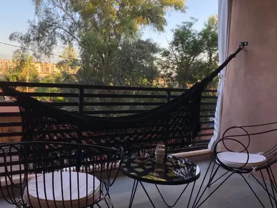 a hammock on a balcony with two chairs and a table at Rooftop Pool, Atlas View, M avenue in Marrakech