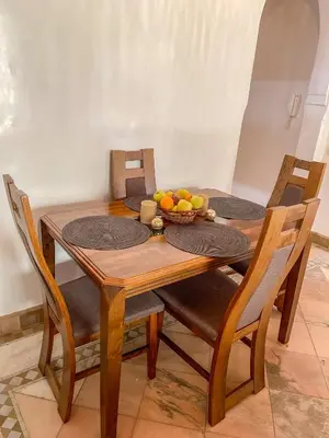 a wooden table with chairs and a bowl of fruit on it at Au cœur de la palmeraie de Marrakech in Marrakech