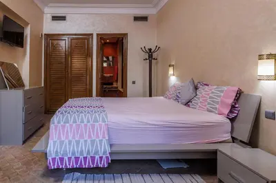 a bedroom with a large bed with pink and purple sheets at Alqantara in Marrakech