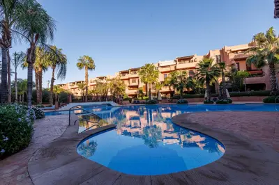 a resort pool with palm trees and a building at Alqantara in Marrakech