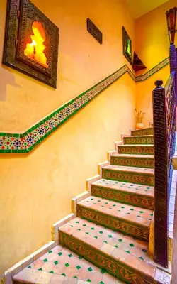 a staircase in a building with a painting on the wall at Riad Kamal prés Medina Marrakech & 3 Piscines & Jacuzzi & Petit-Déjeuner in Marrakech