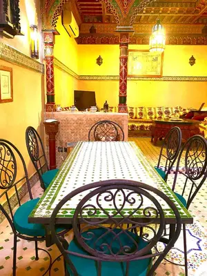 a table and chairs in a room with a bar at Riad Kamal prés Medina Marrakech & 3 Piscines & Jacuzzi & Petit-Déjeuner in Marrakech