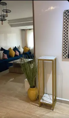 a living room with a table and a vase with a plant at Résidence Elsalam Marrakech in Marrakech