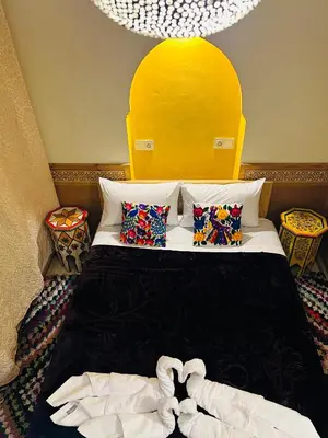 a bedroom with a bed with a yellow headboard at DAR AL NOUR in Marrakech