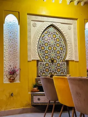 a yellow wall with two chairs and aificantificantificantificantificantificantificantificant at DAR AL NOUR in Marrakech