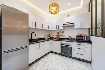 a kitchen with white cabinets and a stainless steel refrigerator at RIAD LE M neuf et contemporain in Marrakech