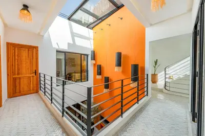 a hallway with an orange accent wall and a door at RIAD LE M neuf et contemporain in Marrakech