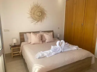 a bedroom with a bed with white sheets and pillows at Bel appart wifi balcon et parking Marrakech centre in Marrakech