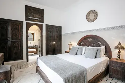 a bedroom with a large bed with white sheets at RIAD ELNOUJOUM in Marrakech