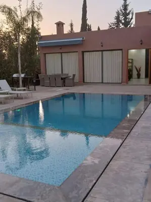 a large blue swimming pool in front of a house at Private Villa with private Chef optional in Marrakech