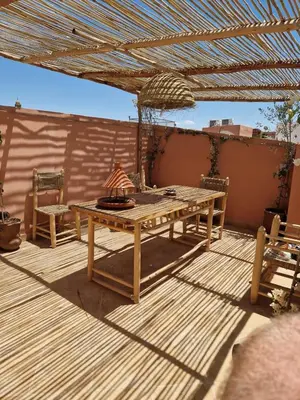 a wooden deck with a table and chairs on a patio at maison noé , residence al quaria ab40 in Marrakech