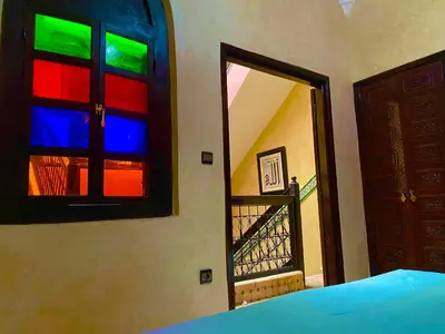 a bedroom with colorful windows and a door with a staircase at Riad Atlas avec jacuzzi 3 piscines au cœur de Marrakech in Marrakech