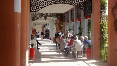 a group of people sitting at tables on a sidewalk at Riad Atlas avec jacuzzi 3 piscines au cœur de Marrakech in Marrakech