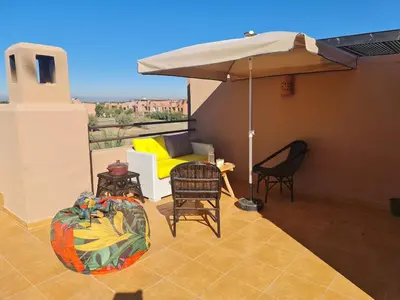 a patio with an umbrella and a table and chairs at Villa avec piscine chauffée & privée, 3 chambres in Sraghna