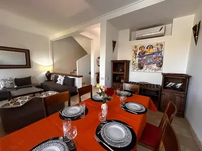 a living room with a table and a couch at Villa avec piscine chauffée & privée, 3 chambres in Sraghna
