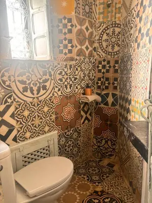a bathroom with a toilet and a bunch of tiles at Riad Sanwa in Marrakech
