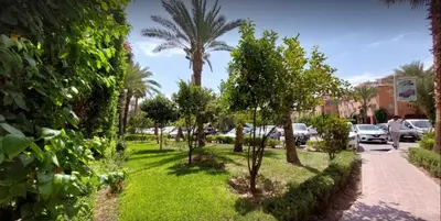 a park with palm trees and a sidewalk at Riad Nezha avec jacuzzi et au cœur de Marrakesh in Marrakech